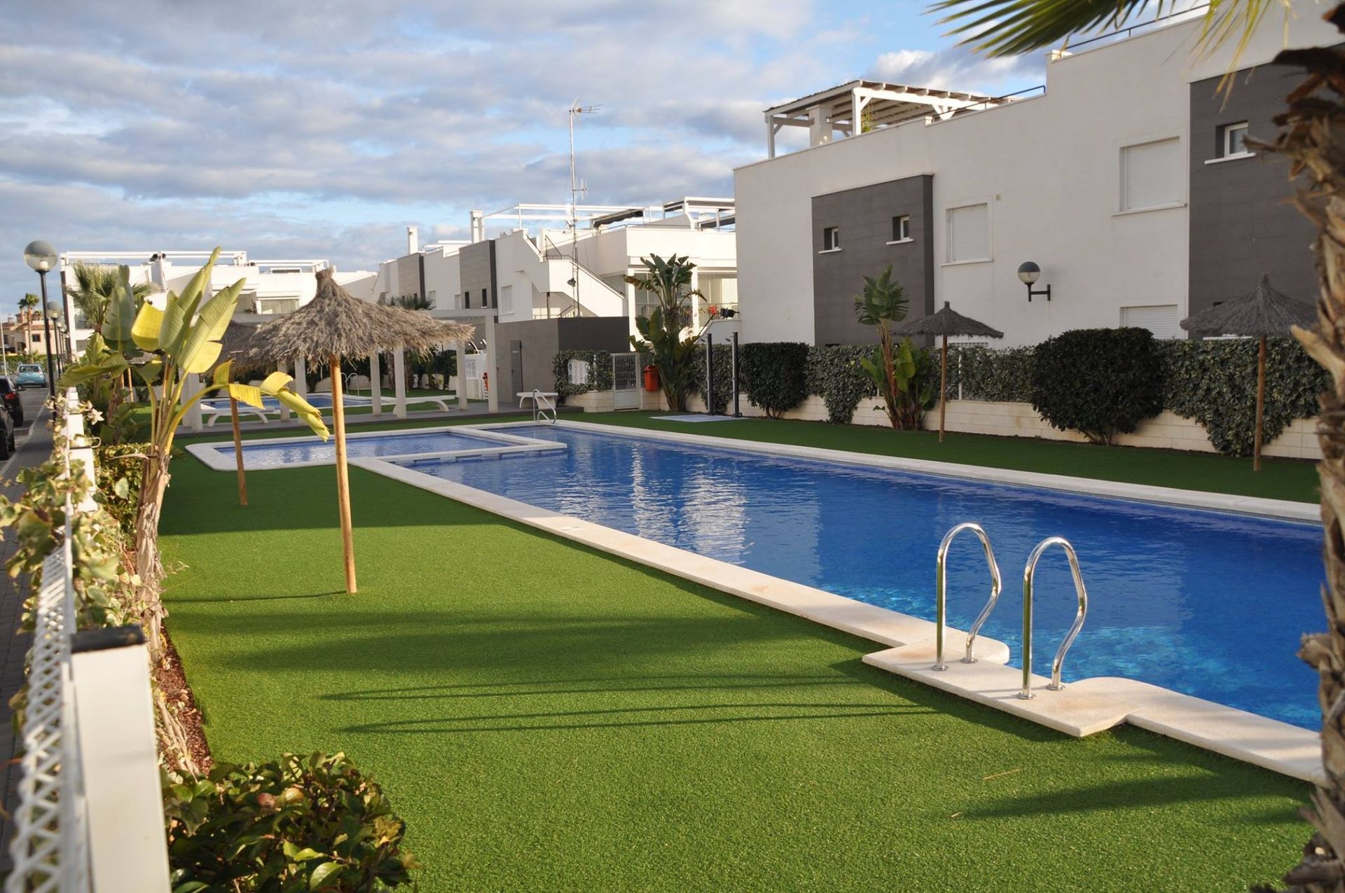 Una gran piscina está rodeada de un exuberante césped verde.