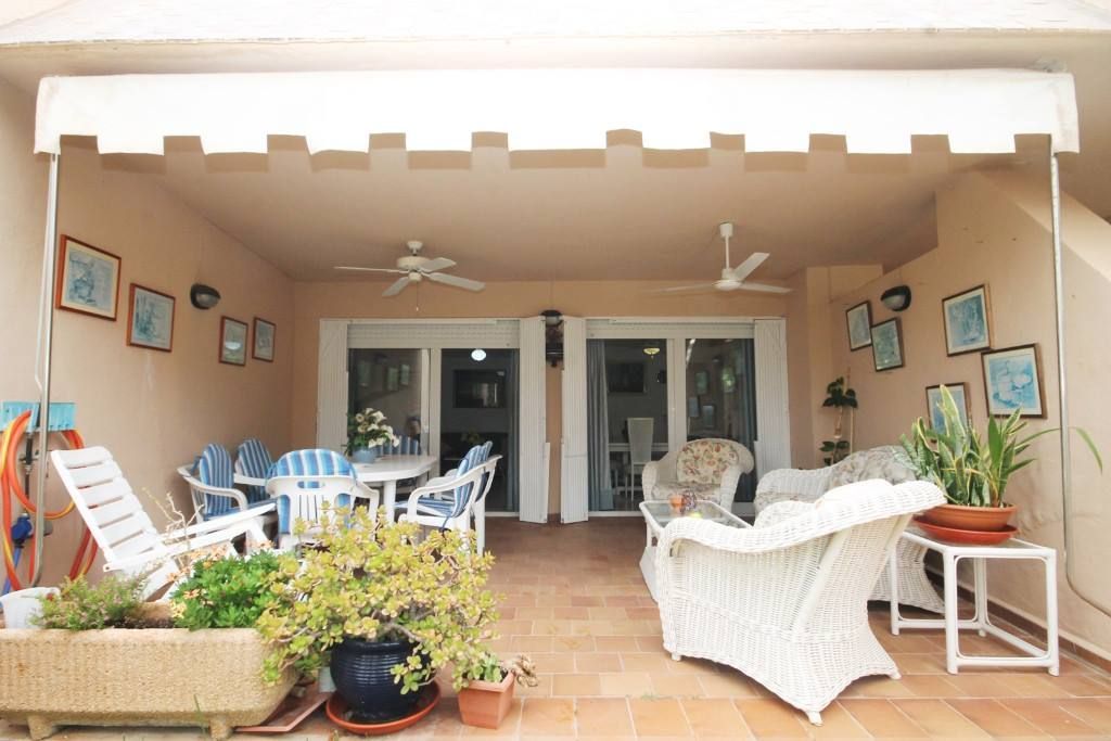 Un patio con muebles blancos y un toldo blanco.
