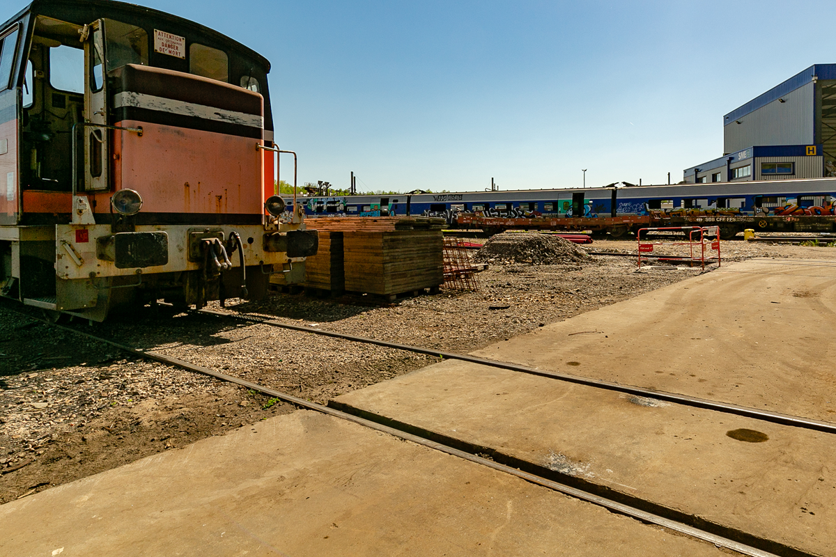 Wagons et matériaux de construction le long d'un chemin en béton dans une recyclerie, sous un ciel dégagé