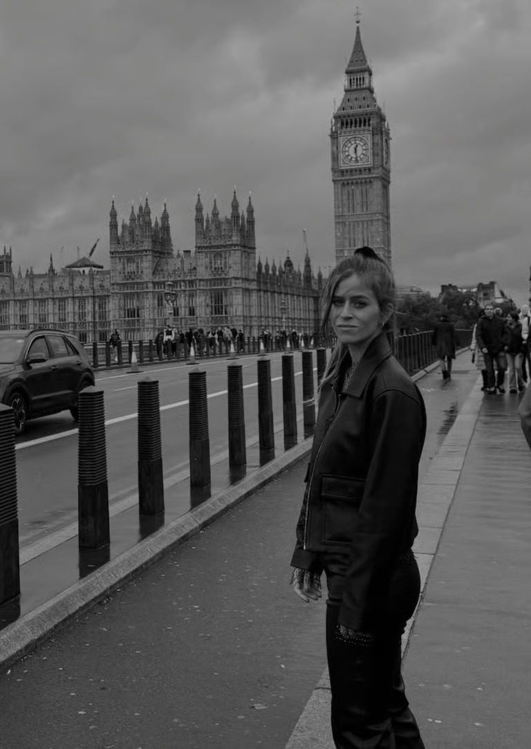 Une personne se tient sur un trottoir devant la tour Elizabeth et Big Ben à Londres, par temps nuageux.