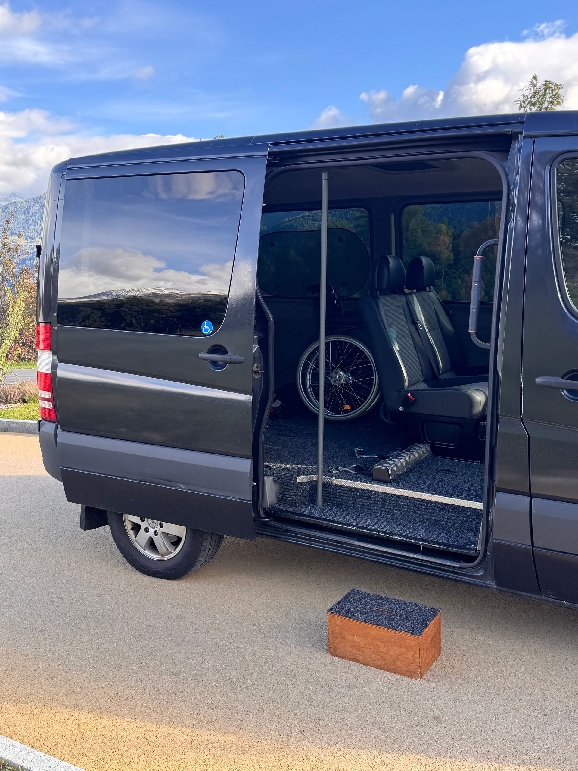Une camionnette gris foncé avec une porte latérale ouverte comportant un siège passager.