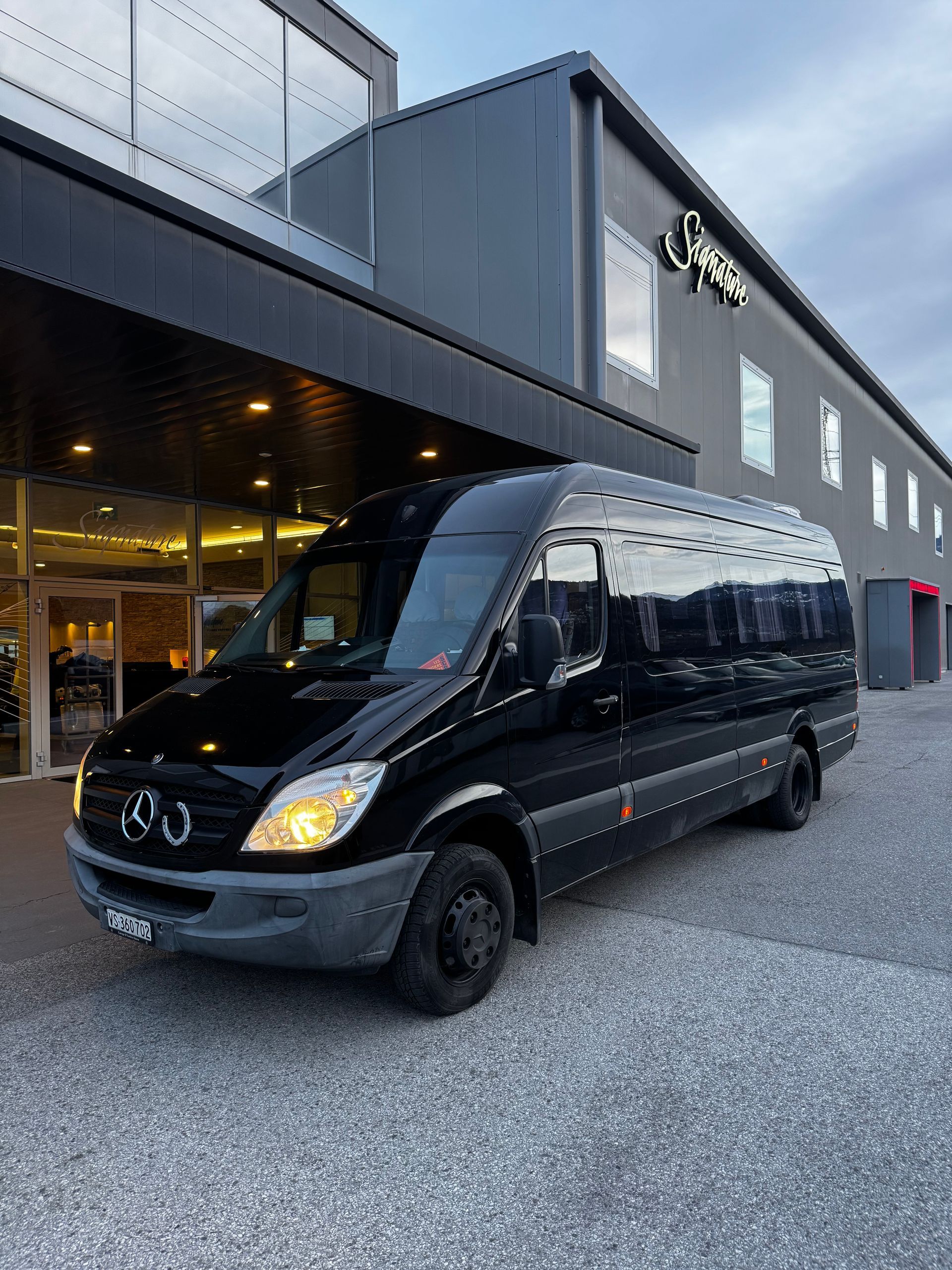 Une camionnette noire pour passagers avec une porte coulissante ouverte et un marchepied en bois.
