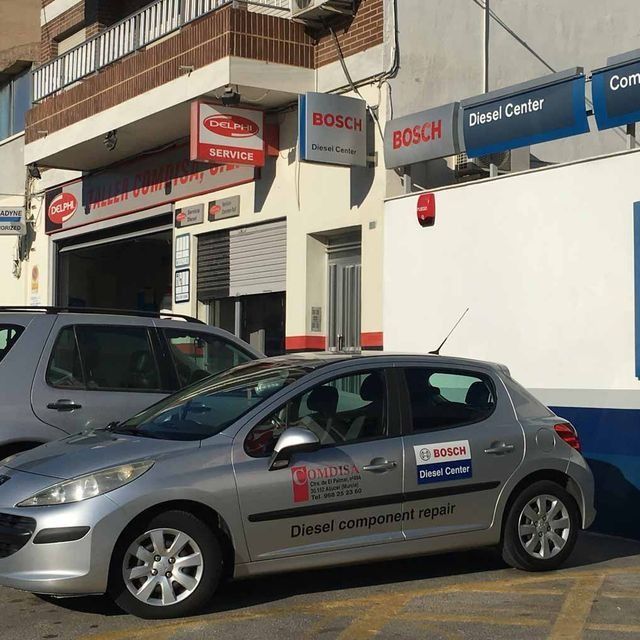 Un coche plateado está aparcado delante de un centro diésel Bosch.