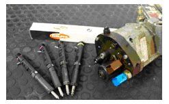 Un grupo de inyectores colocados junto a una bomba de combustible sobre una mesa.