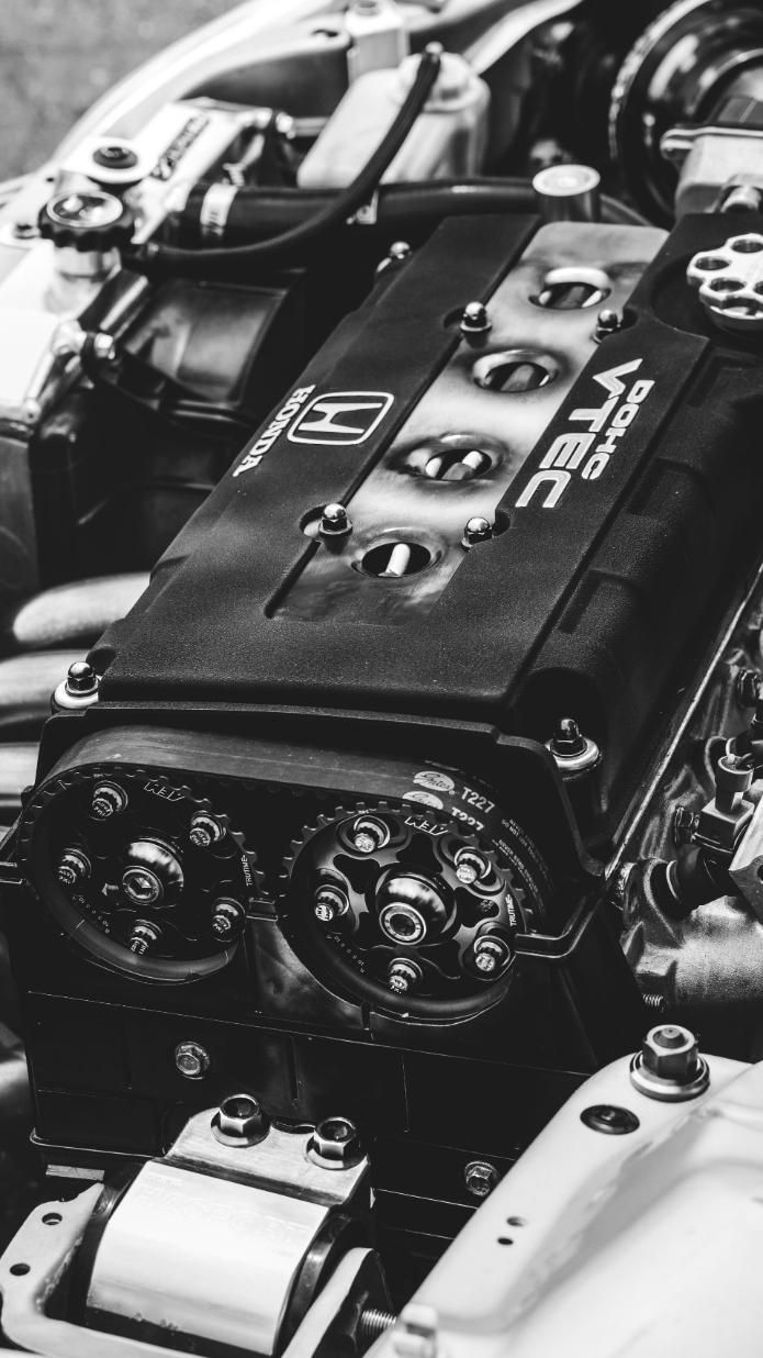Primer plano de una cubierta de motor de automóvil negra con herrajes plateados en el compartimento del motor.
