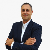 Homme en blazer bleu marine, les bras croisés, sur fond blanc