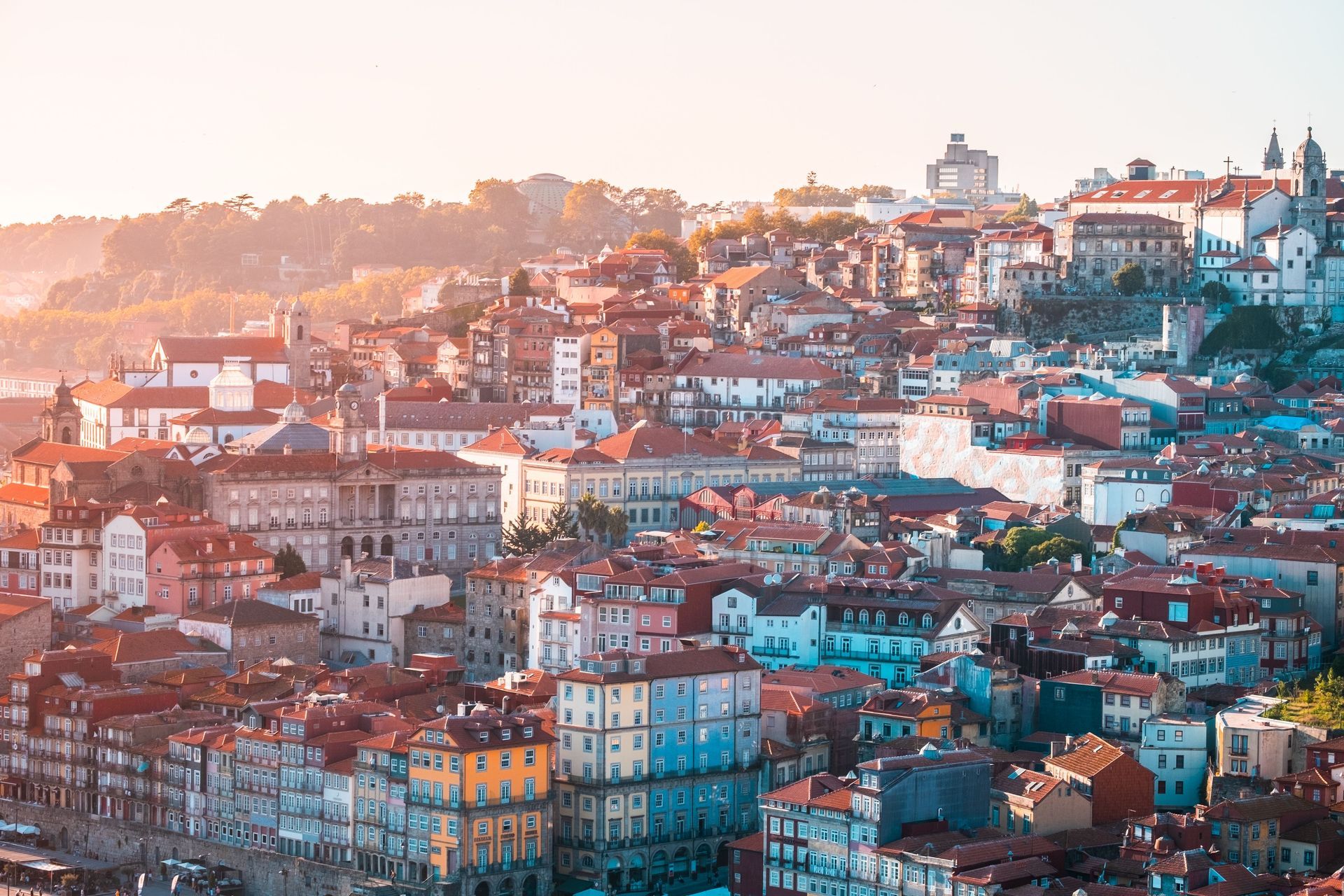 Paysage urbain ensoleillé à flanc de colline, avec des bâtiments colorés serrés les uns contre les autres et une église à dôme au loin