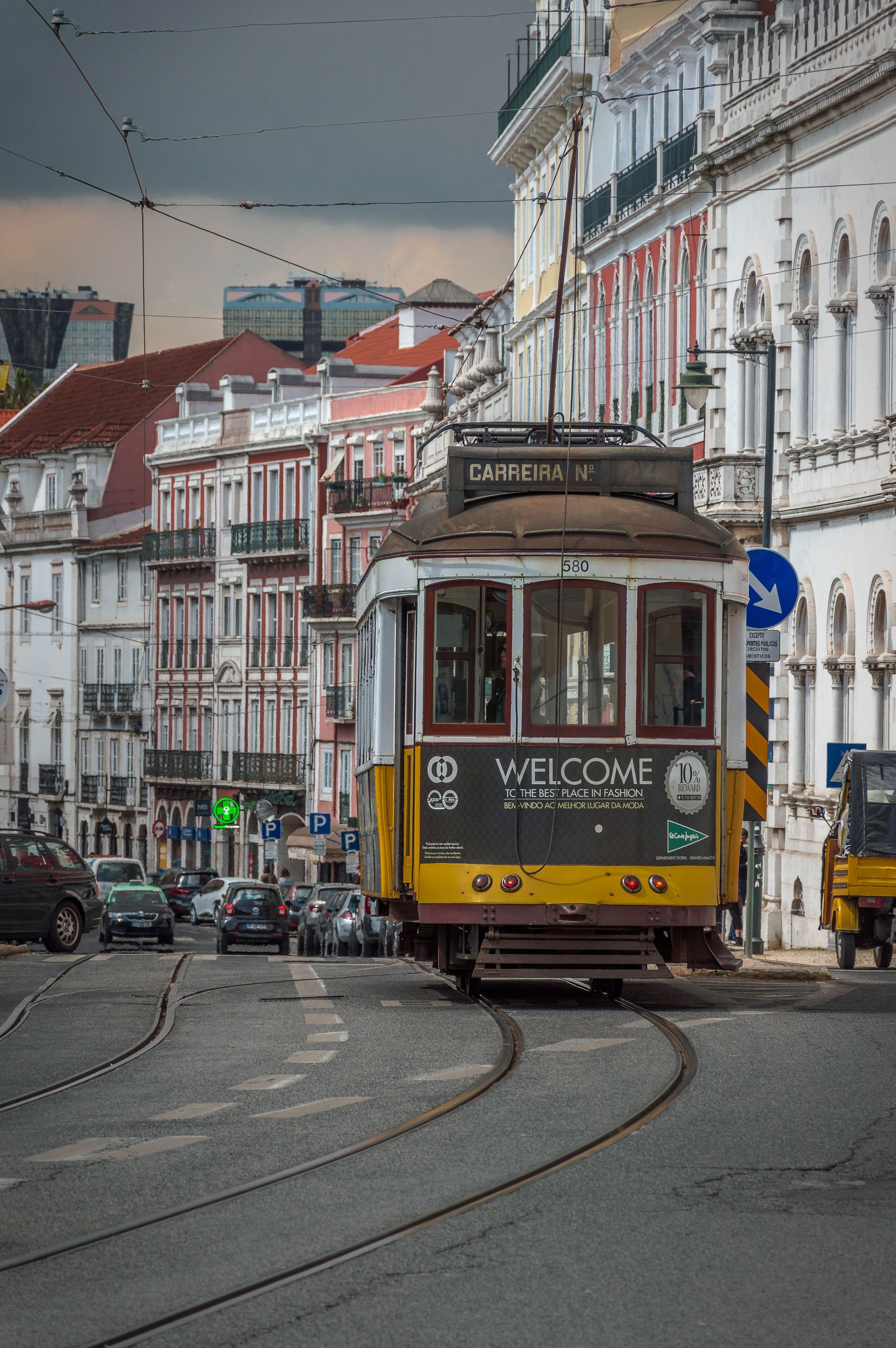 Tramway jaune circulant sur des rails sinueux dans une rue historique bordée de bâtiments blancs