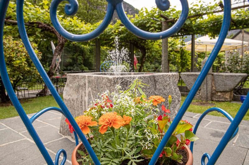 Una sedia blu con dei fiori in un vaso davanti a una fontana.
