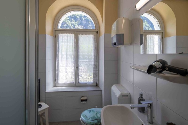Un bagno con wc, lavandino, specchio e finestra.