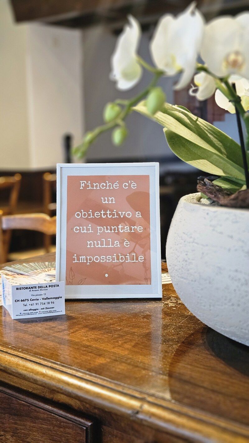 Un cartello su un tavolo accanto a un vaso di fiori.