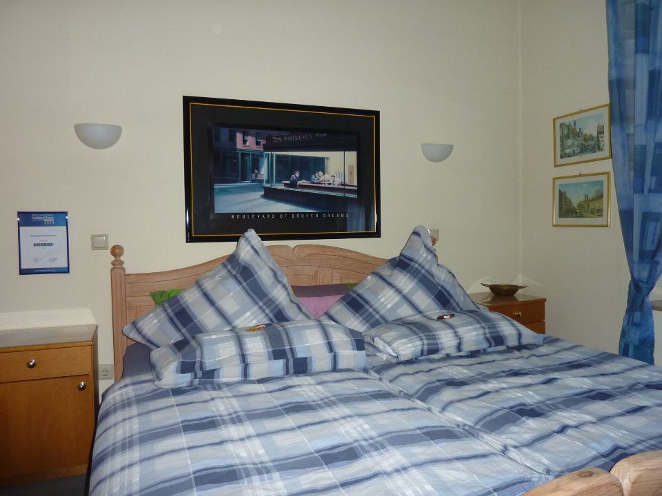 Zimmer mit Doppelbett, Nachtschränkchen und mehreren Bildern