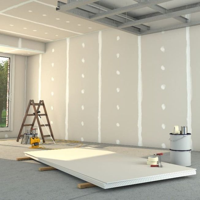 Una habitació en construcció amb una escala i galledes de pintura