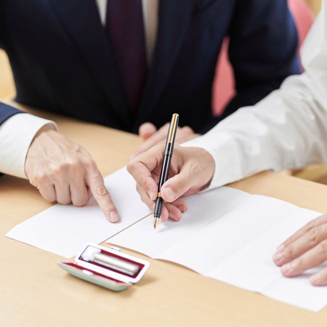 Un home i una dona asseguts a una taula escrivint en un tros de paper