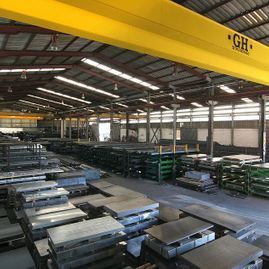 Un gran almacén lleno de muchas piezas de metal y una grúa amarilla.