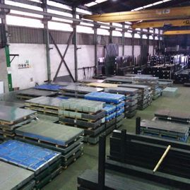 Un gran almacén lleno de láminas de metal y paletas.