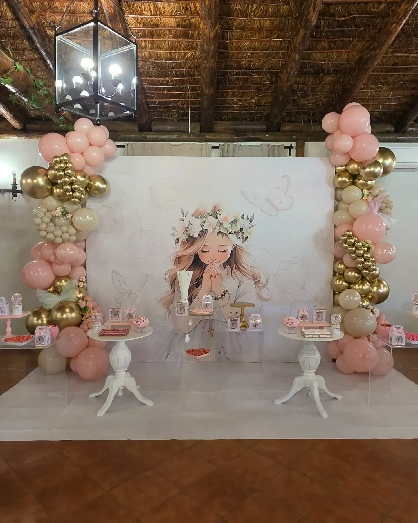 Fondo floral de color rosa pastel y dorado para fiestas, con mesas de postres y columnas de globos en un salón rústico.