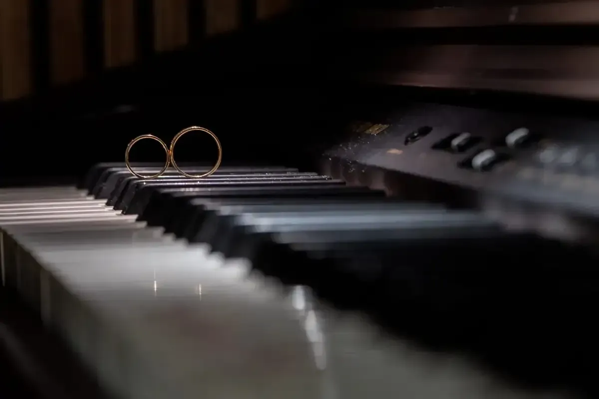 Teclas de piano con un par de anillos de oro sobre ellas, en penumbra.