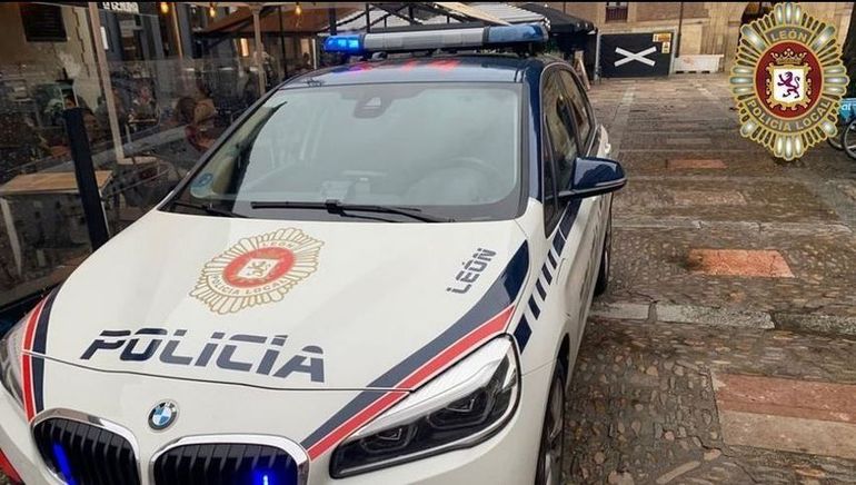 Un coche de policía blanco y rojo está estacionado frente a un edificio.