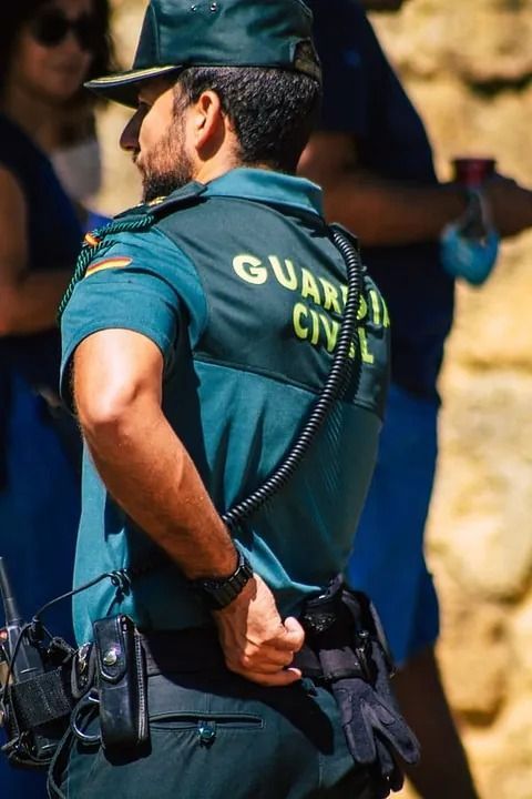 Un hombre con uniforme de guardia civil está de pie entre una multitud.