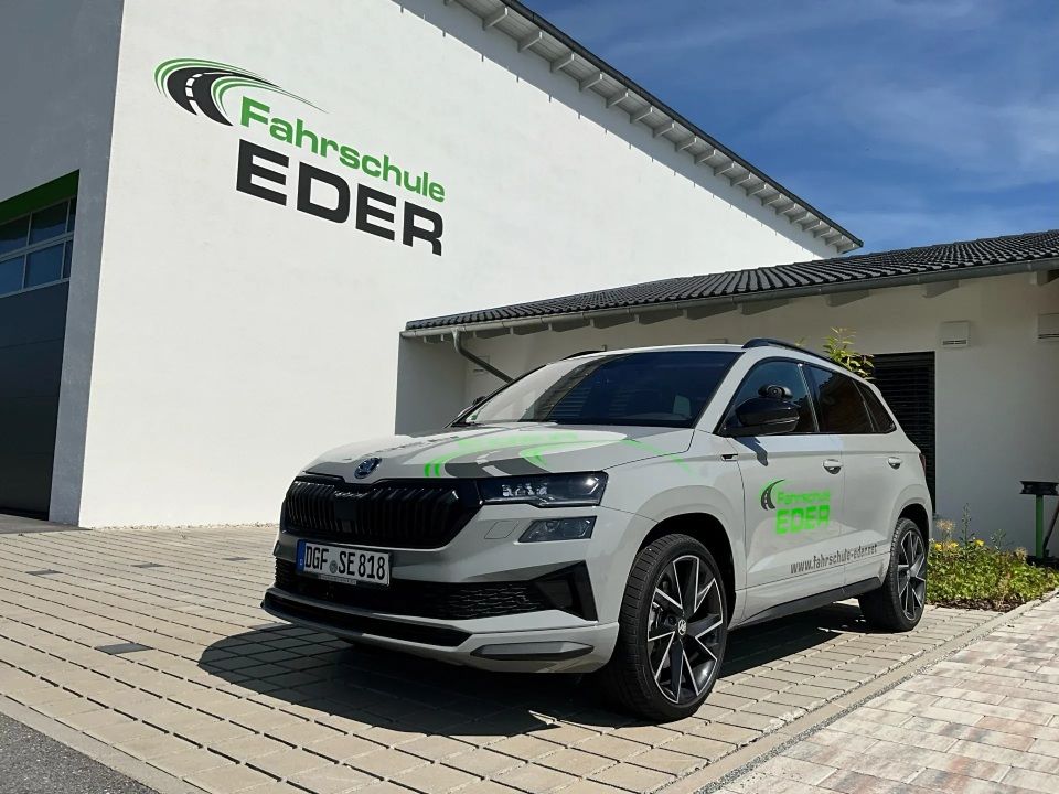 Ein grauer Skoda SUV parkte vor einem Fahrschulgebäude mit der Aufschrift „Fahrschule EDER“.