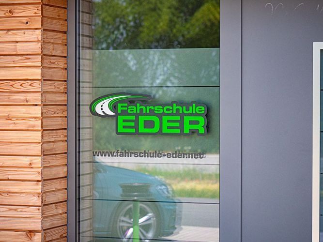 Das Schild der Fahrschule Eder prangt auf einer Glastür. Grünes 