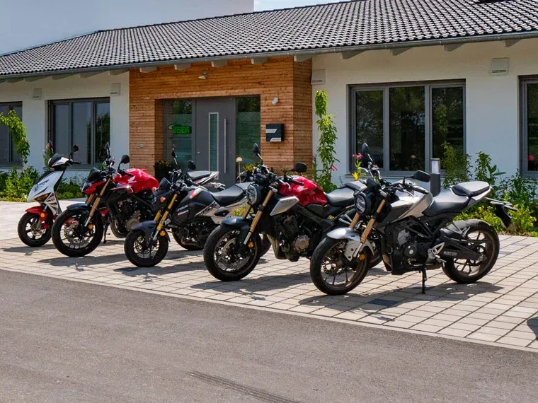 Fünf Motorräder parkten vor einem Gebäude mit einem Eingang aus Holz.