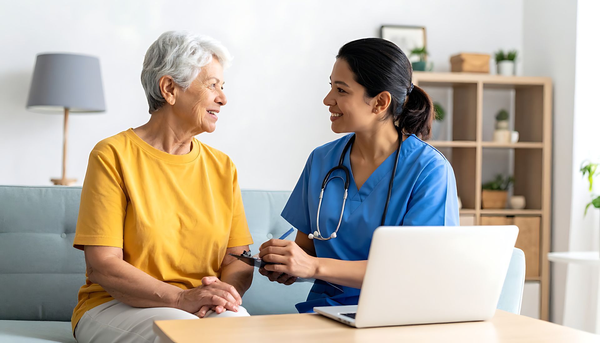 Un professionnel de santé discute avec un patient dans une pièce lumineuse, un ordinateur portable étant posé sur la table.