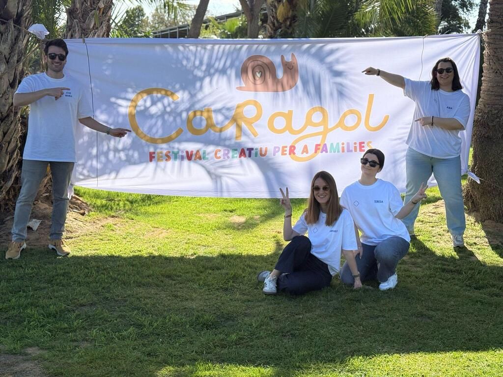 Un grupo de personas posa para una fotografía delante de una gran pancarta blanca.