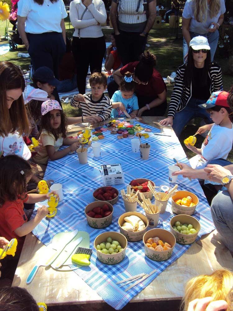 Un grupo de personas está sentado alrededor de una mesa con tazones de fruta encima.