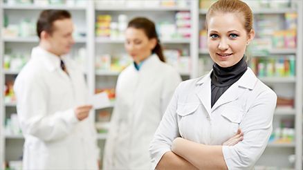 Una farmacéutica está de pie en una farmacia con los brazos cruzados.