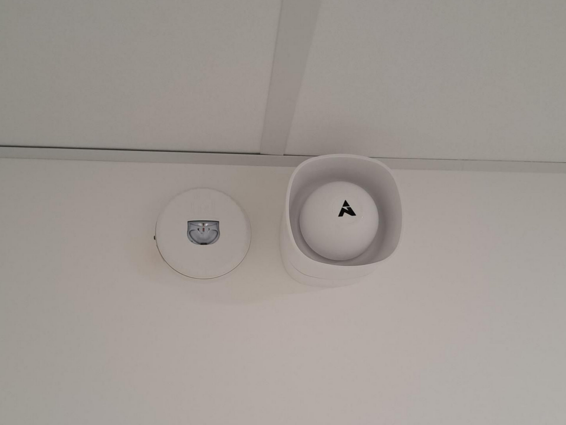 Alarme et détecteur de sécurité blancs fixés au mur.