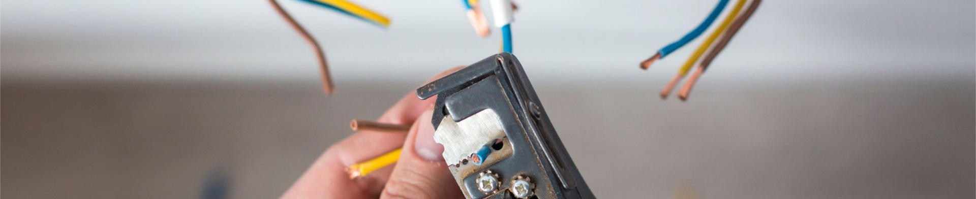 Une personne raccorde des câbles électriques à une boîte de jonction.