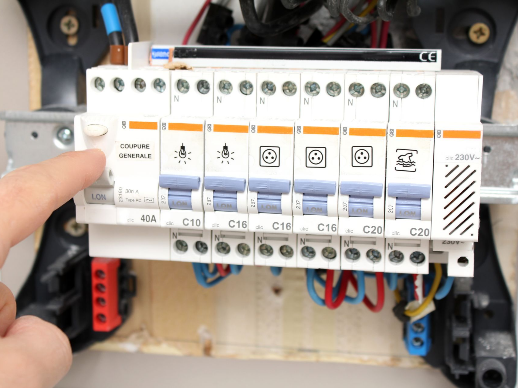 Doigt pointant vers un disjoncteur dans un tableau électrique.