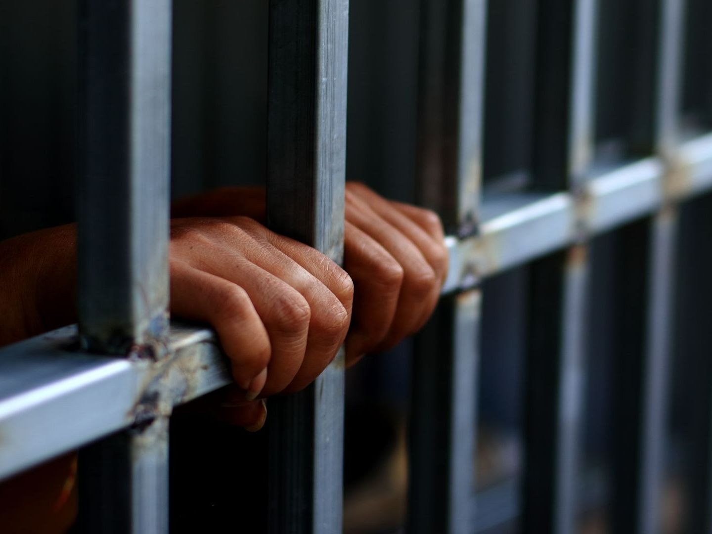 Mains de détenu sur une grille de prison