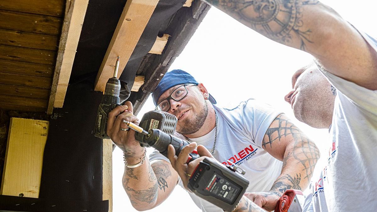 Ein Mann mit einer Tätowierung auf dem Arm arbeitet an einem Rohr