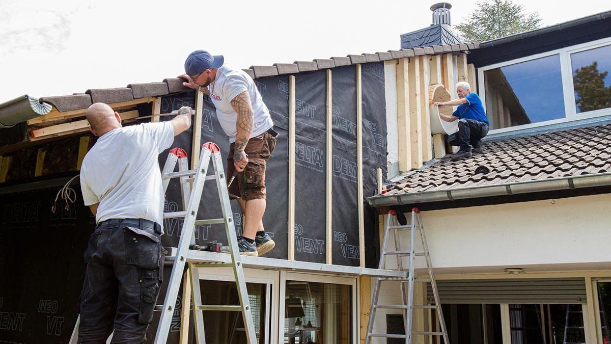 Eine Gruppe Männer arbeitet an der Seite eines Hauses.