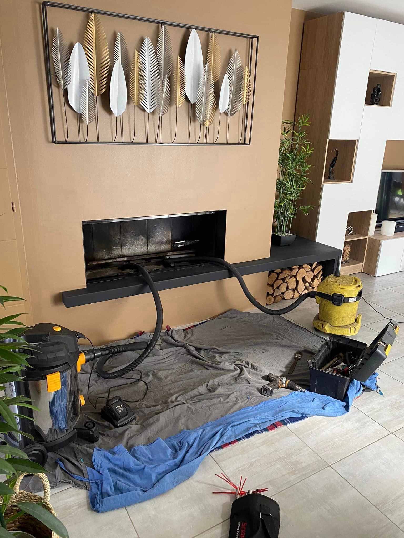 Salon avec mur TV, tableaux décoratifs en forme de poissons, outils, câbles et bâches lors d'un projet de bricolage.