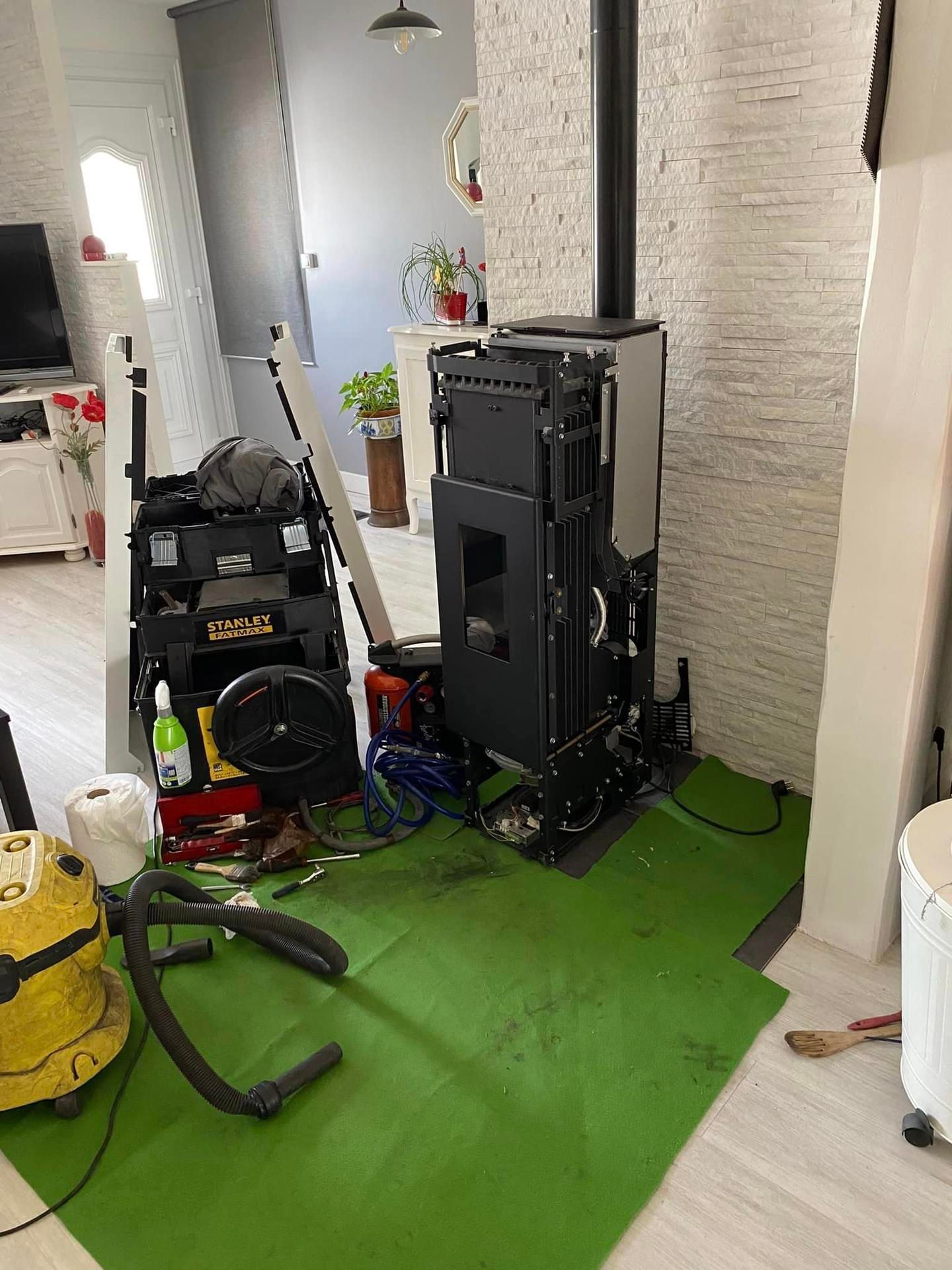 Des appareils et des câbles jonchent un tapis vert dans un couloir, à côté d'un mur de briques.