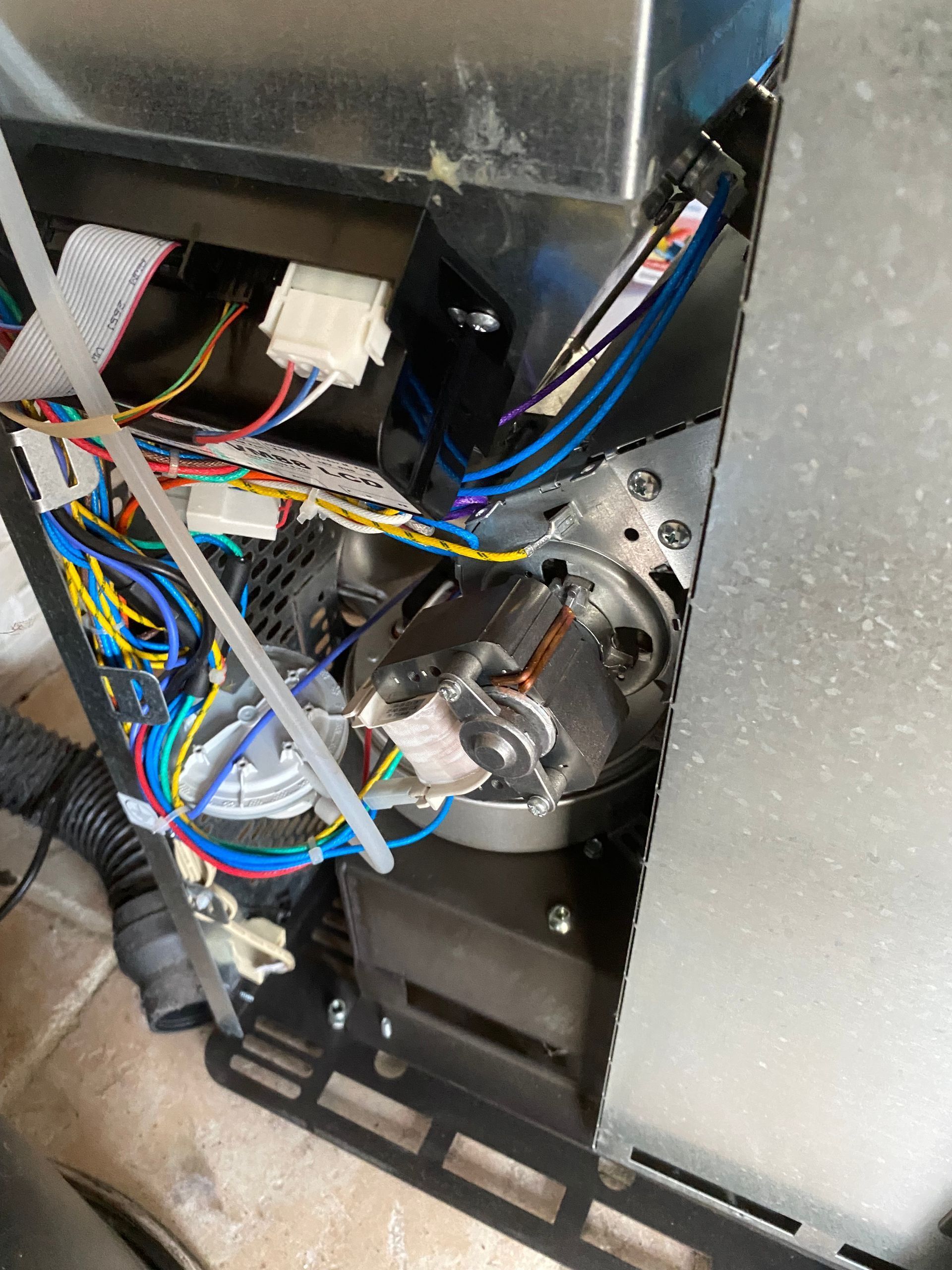 Câblage et composants à l'intérieur d'un bloc moteur de poêle.