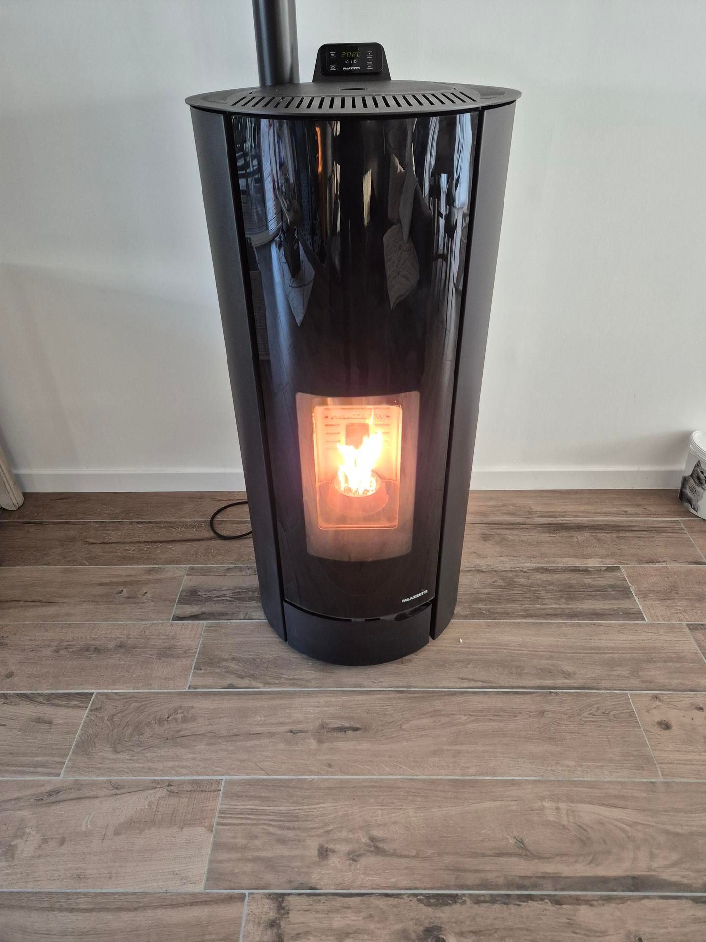 Poêle à granulés noirs avec un feu incandescent dans une pièce au parquet.
