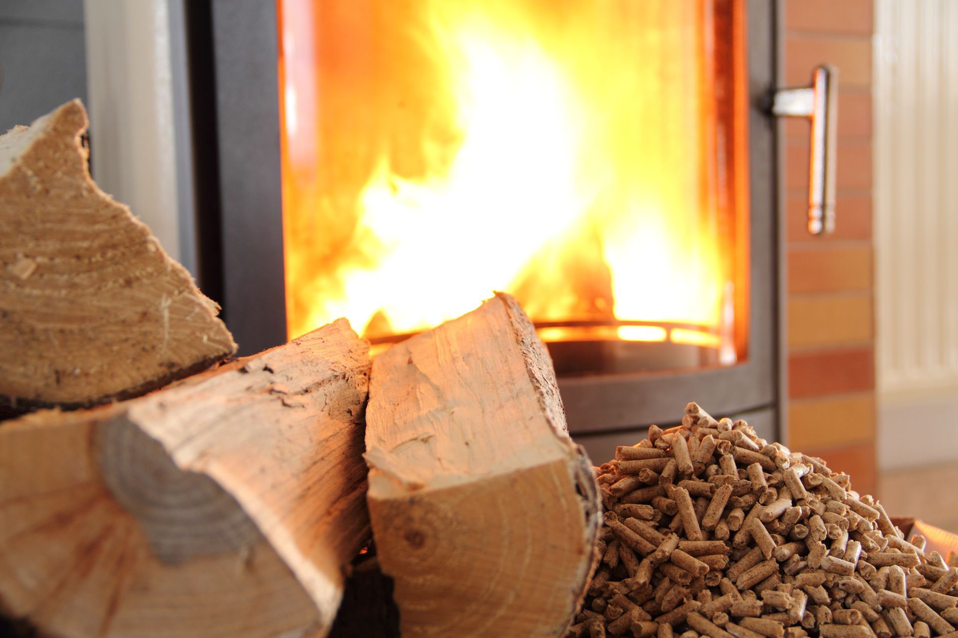 Bûches et granulés de bois près d'un poêle avec flammes vives.