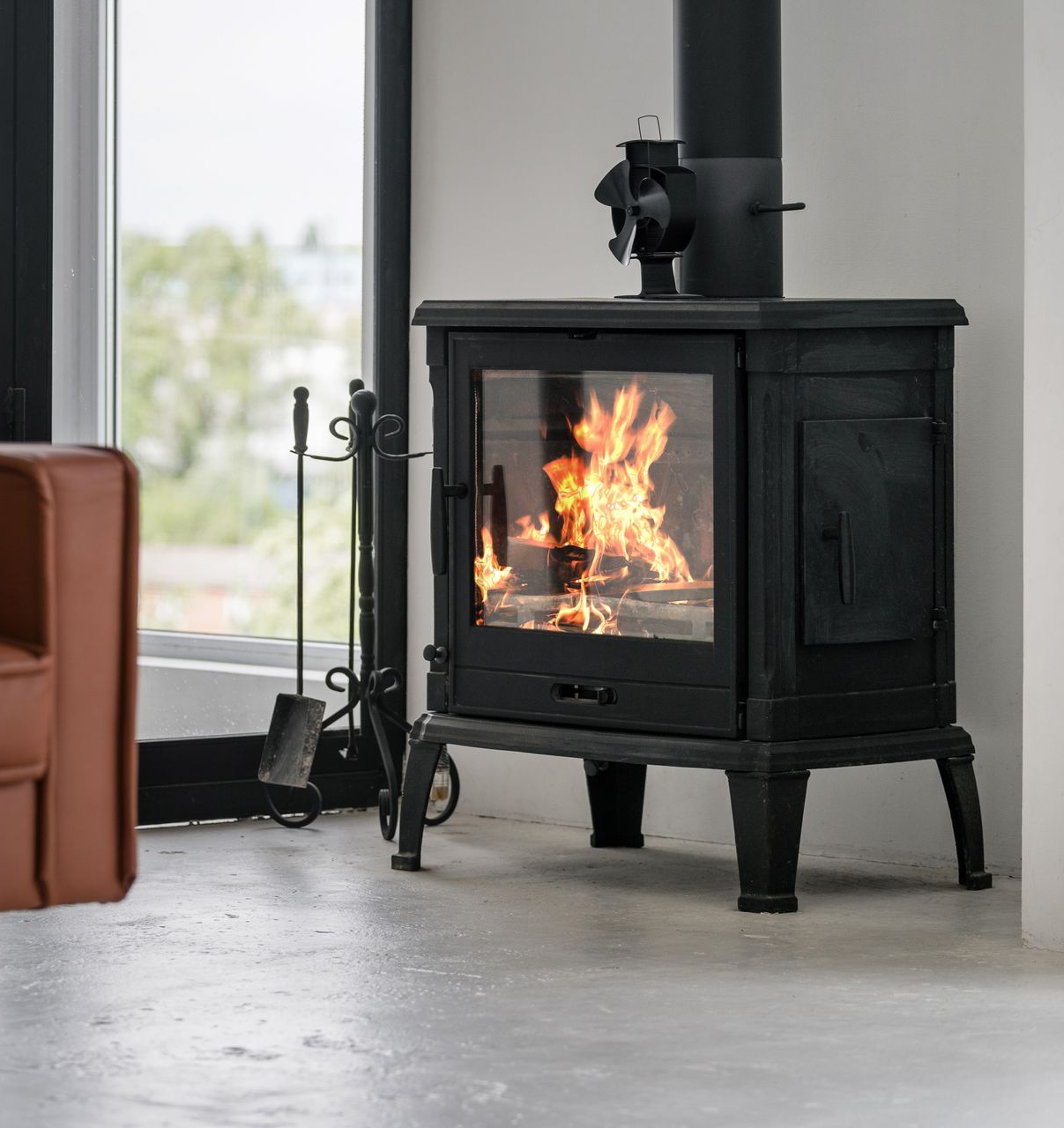 Poêle à bois noir avec flammes visibles dans une pièce moderne et lumineuse.