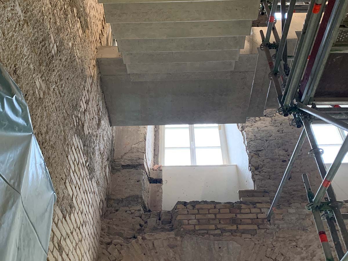 Zwei Bauarbeiter betrachten einen Bauplan in einem im Bau befindlichen Gebäude.