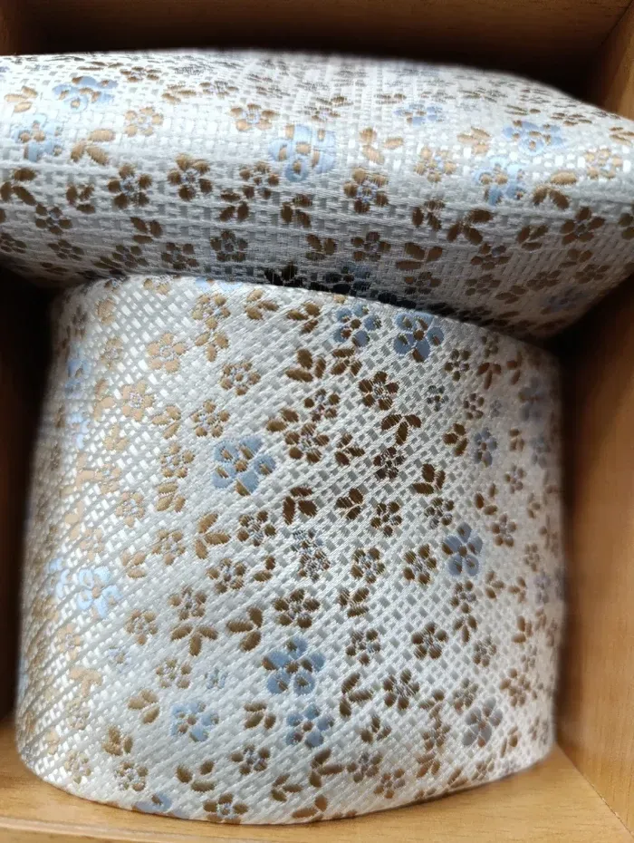 Dos piezas con estampado floral blanco: un cilindro y un cuadrado en la parte superior, dentro de una caja de madera.