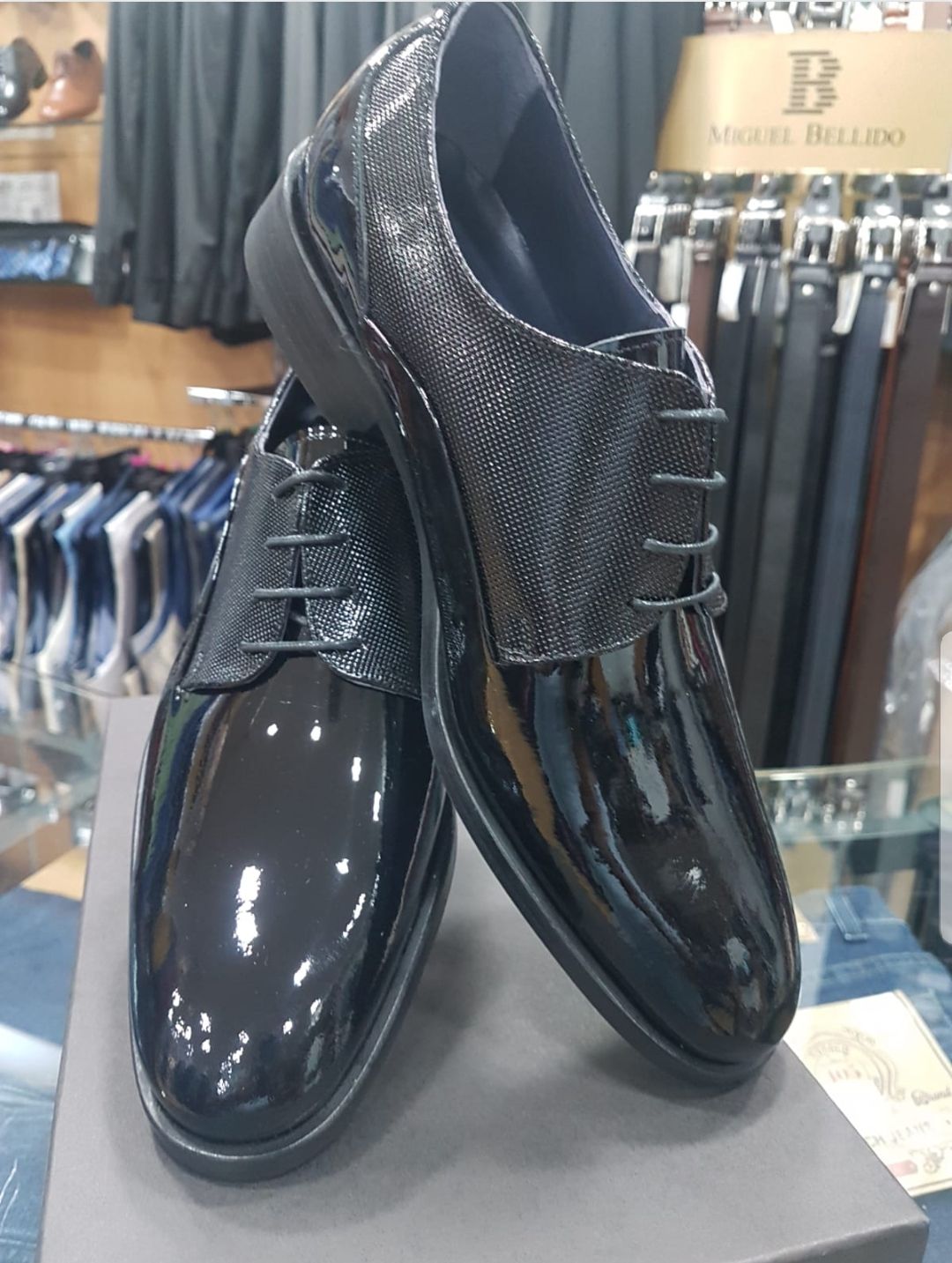 Zapatos de vestir para hombre en piel charol negra, con lengüeta texturizada, presentados en caja.
