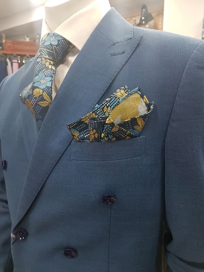 Traje azul cruzado con corbata floral y pañuelo de bolsillo. El traje está sobre un maniquí.