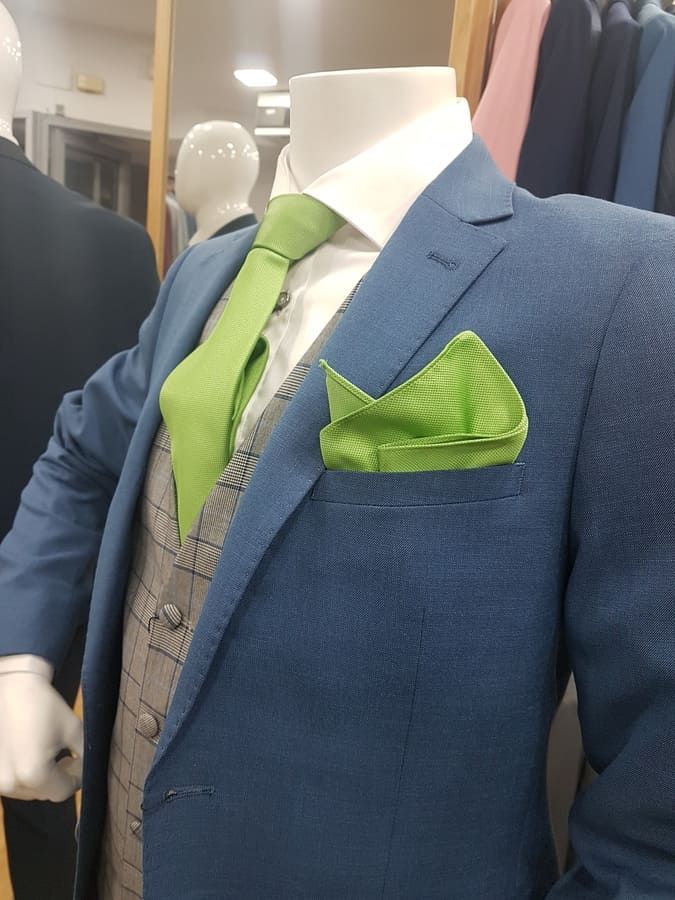 Maniquí con traje azul, corbata verde, pañuelo de bolsillo y chaleco a cuadros.