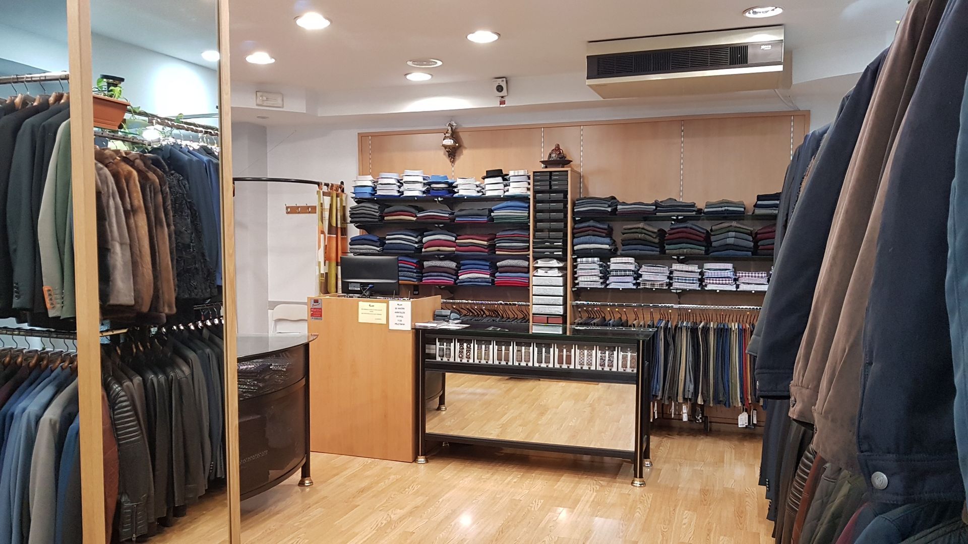 Interior de tienda de ropa con estantes de chaquetas y estantes de ropa doblada.