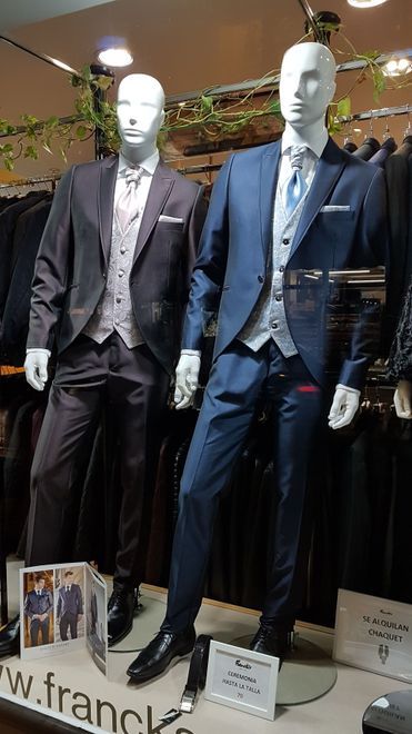 Dos maniquíes en un escaparate, con trajes formales. Uno es marrón oscuro y el otro azul.